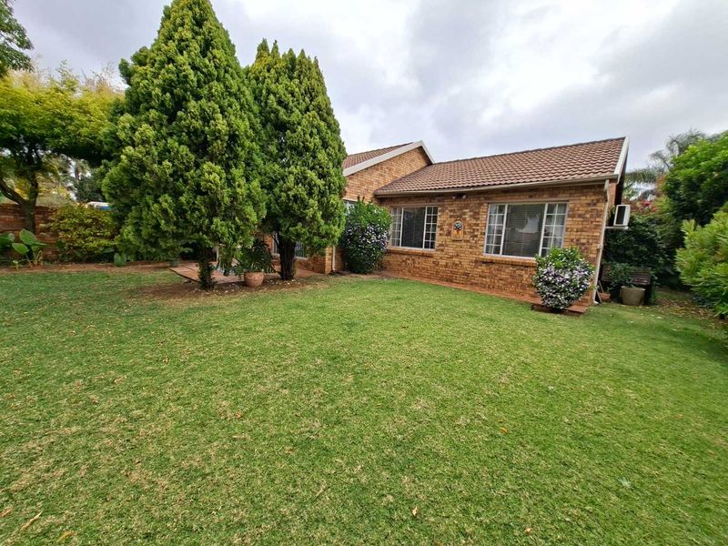 A view of the rear exterior of the townhouse, featuring a brick facade, tiled roof, and a well-maintained garden area.