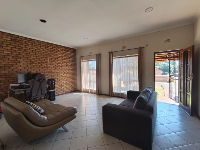 Spacious living room featuring an exposed brick wall, ceramic tiled flooring, and direct access to the exterior through a timber door.
