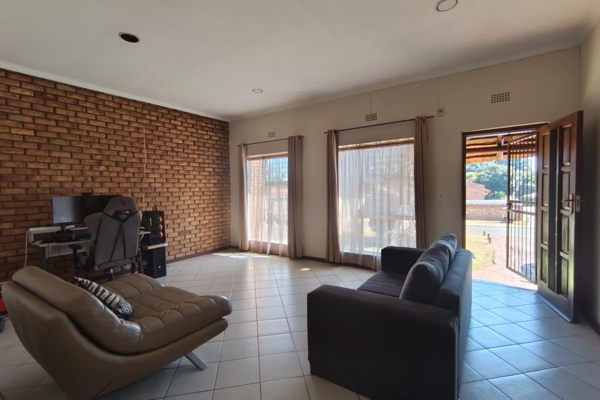 Spacious living room featuring an exposed brick wall, ceramic tiled flooring, and direct access to the exterior through a timber door.