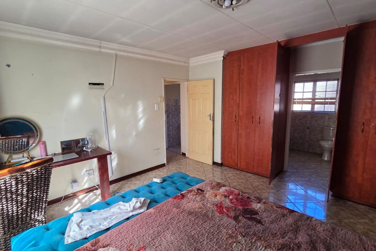 A bedroom featuring built-in wooden wardrobes, tiled flooring, and an en-suite bathroom access point.