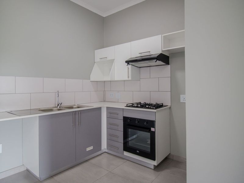 A clean, modern kitchen featuring built-in cabinetry, a gas hob, an integrated oven, and a stainless steel sink with a tiled backsplash.