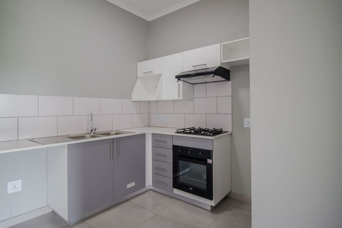 A clean, modern kitchen featuring built-in cabinetry, a gas hob, an integrated oven, and a stainless steel sink with a tiled backsplash.