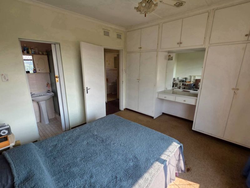 Bedroom featuring extensive built-in cabinetry with integrated vanity and an en-suite bathroom with a pedestal basin.