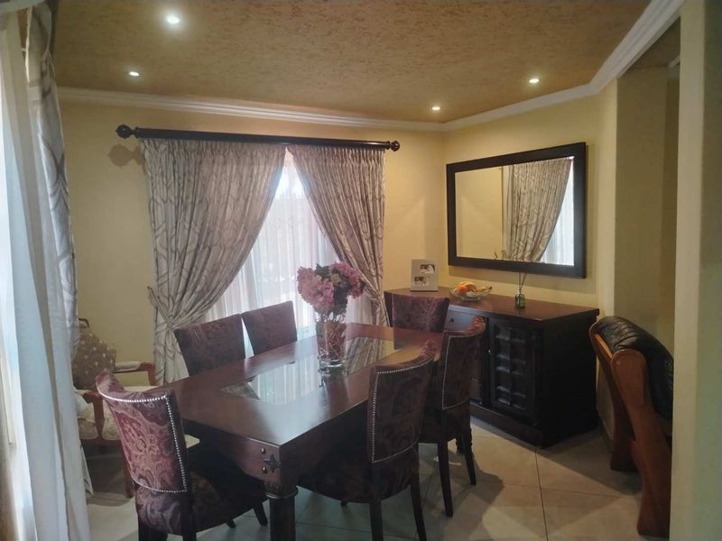 A formal dining room featuring tiled flooring, recessed downlighting, and decorative crown molding, providing a comfortable space for family meals and entertaining.
