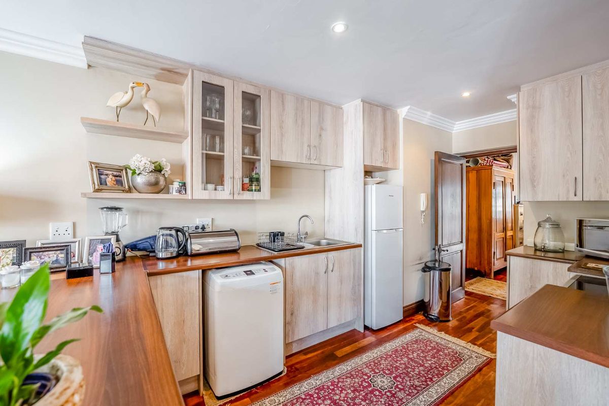 A functional kitchen featuring light wood-finish cabinetry, warm timber countertops, and hardwood flooring, offering a practical layout with integrated sink and storage solutions.