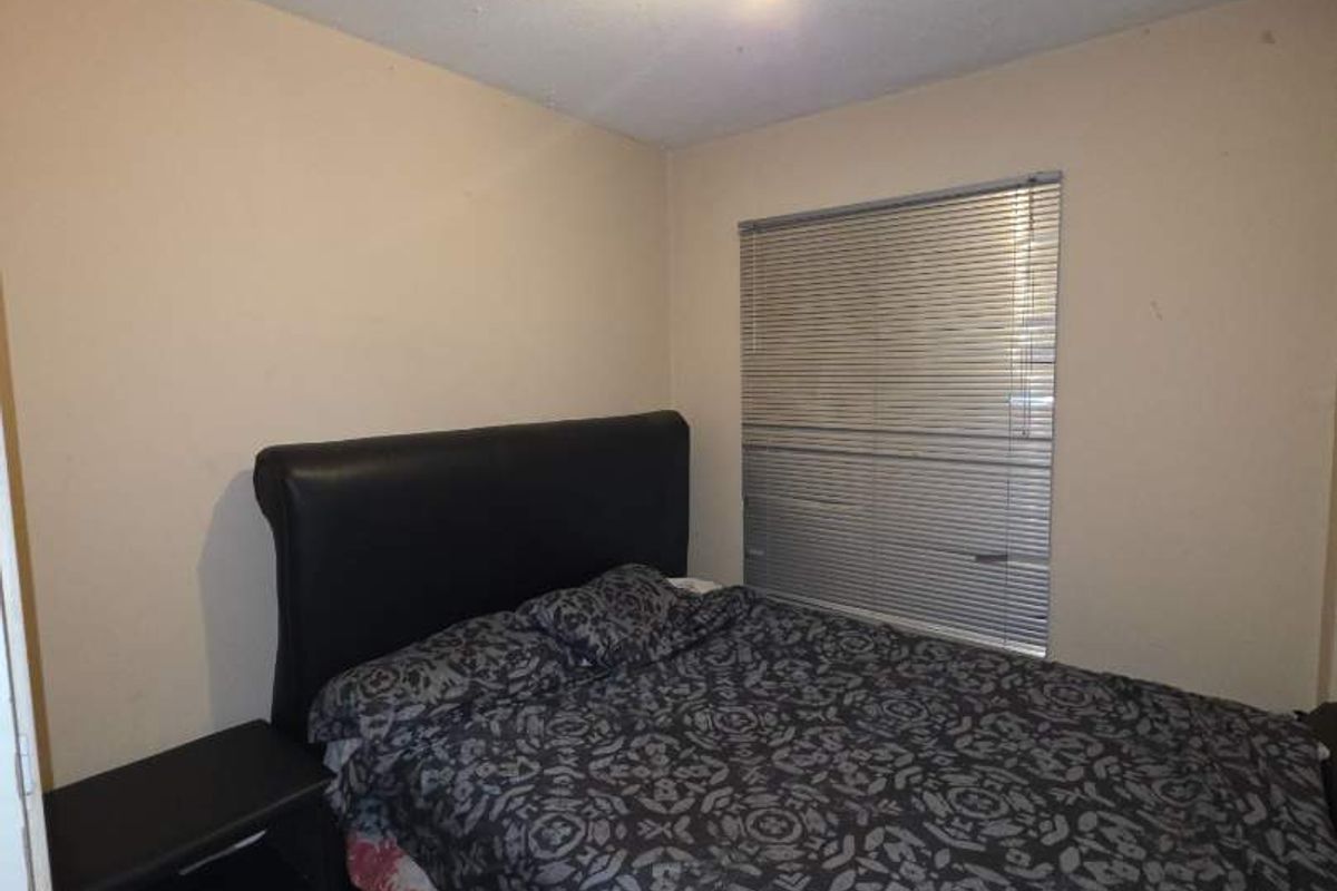 A compact bedroom featuring tiled flooring, venetian blinds, and a central ceiling light fixture, requiring minor cosmetic updates to the walls and ceiling.