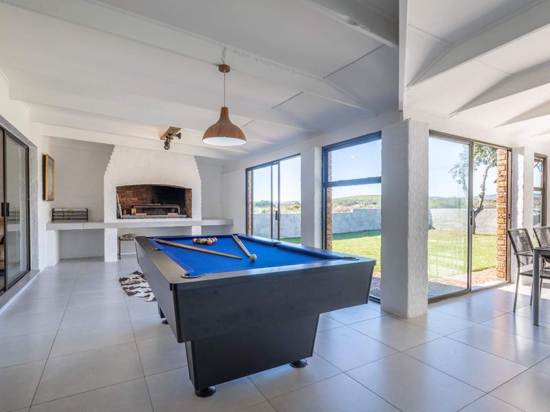 Spacious open-plan entertainment area featuring a built-in braai, tiled flooring, and large sliding glass doors providing seamless access to the garden.