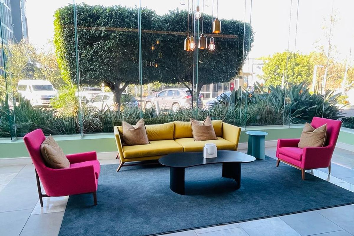 A bright, modern lobby or lounge area featuring floor-to-ceiling glass windows, tiled flooring, and contemporary pendant lighting.