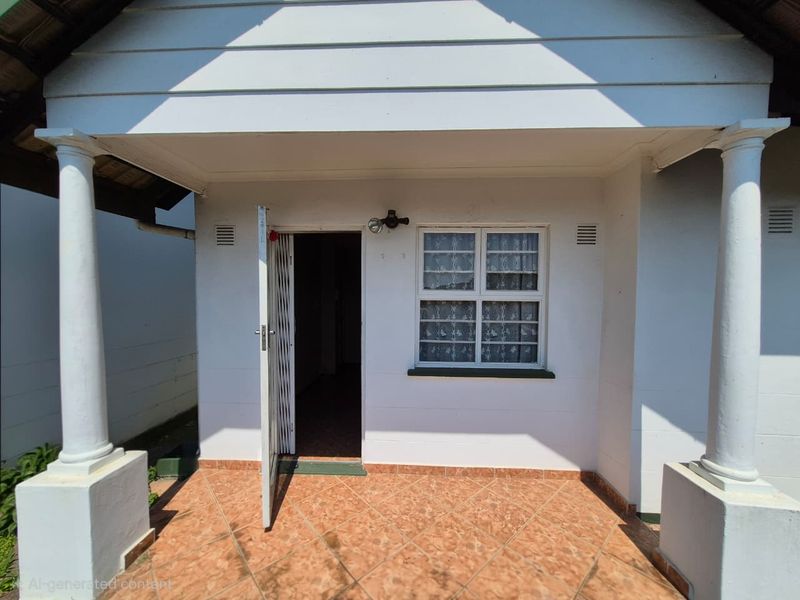 Front entrance of the townhouse featuring a covered porch with columns, tiled flooring, and a security gate.