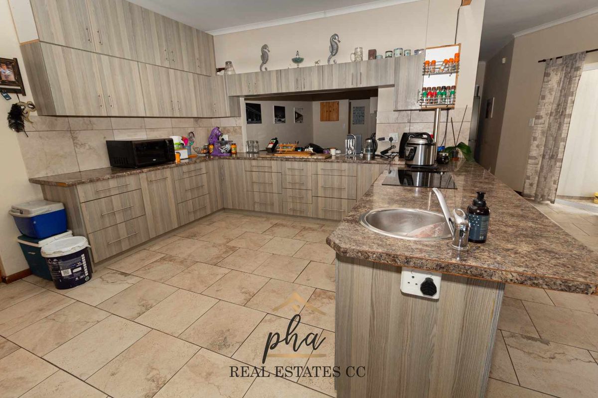 A functional kitchen featuring wood-look cabinetry, granite-style countertops, a breakfast bar with integrated sink, and tiled flooring throughout.