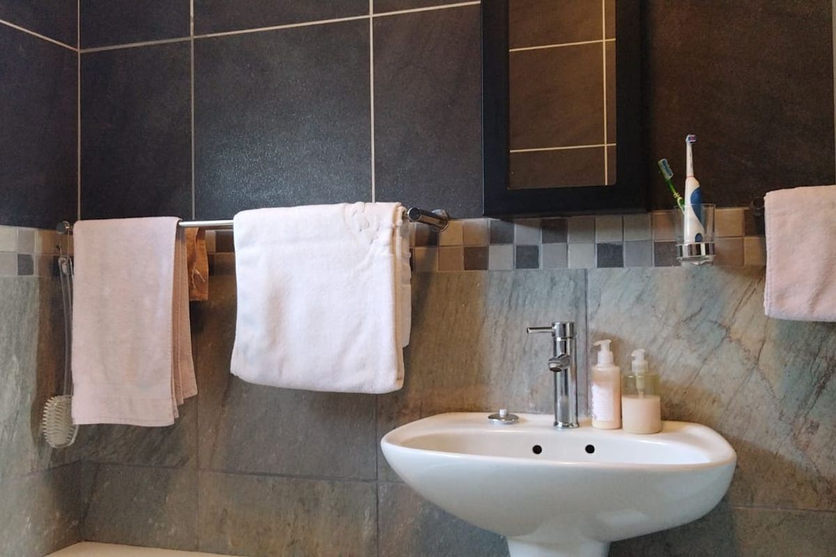 A bathroom featuring a pedestal sink, chrome faucet, and decorative wall tiling with a built-in medicine cabinet.