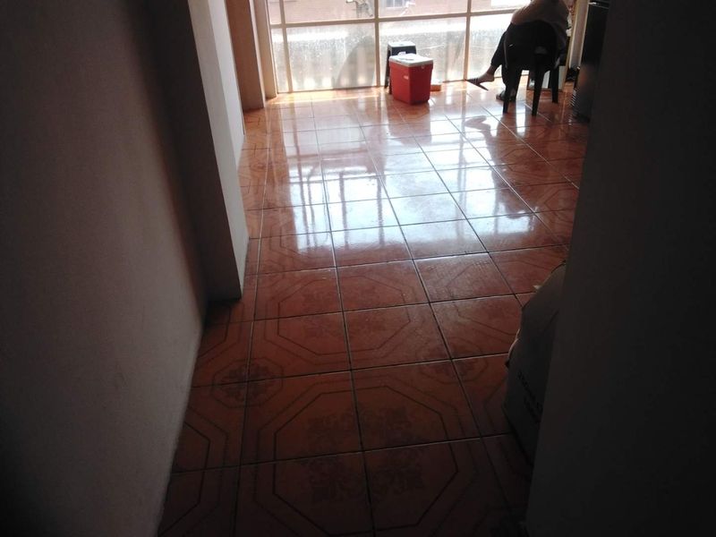 An empty living area featuring ceramic floor tiles and a large glass sliding door providing natural light.