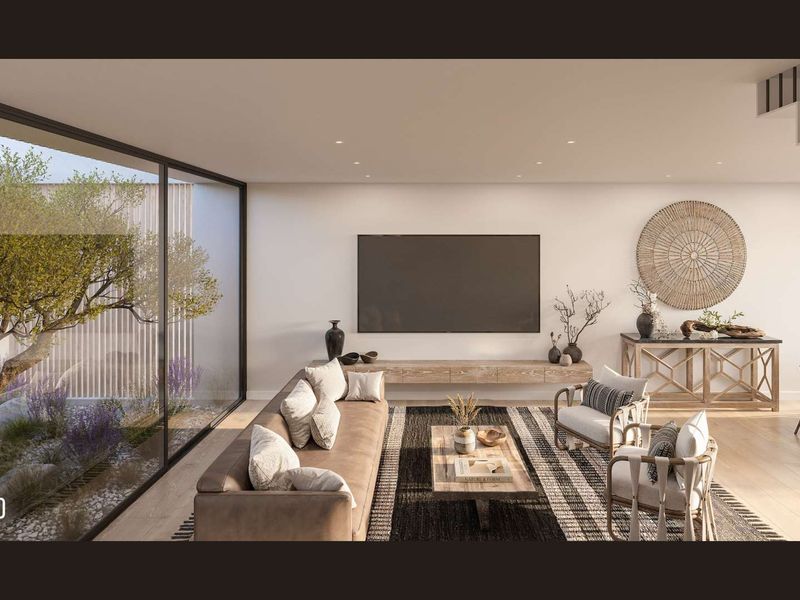 Modern open-plan living area featuring large floor-to-ceiling glass doors overlooking a private courtyard, recessed lighting, and a sleek floating media console.