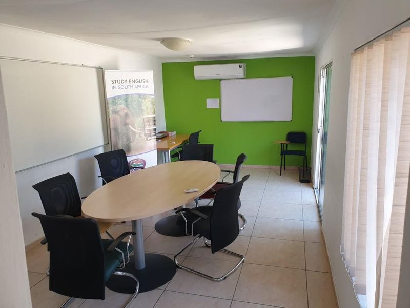 A functional office space featuring tiled flooring, wall-mounted whiteboard, and an air conditioning unit, suitable for meetings or educational purposes.