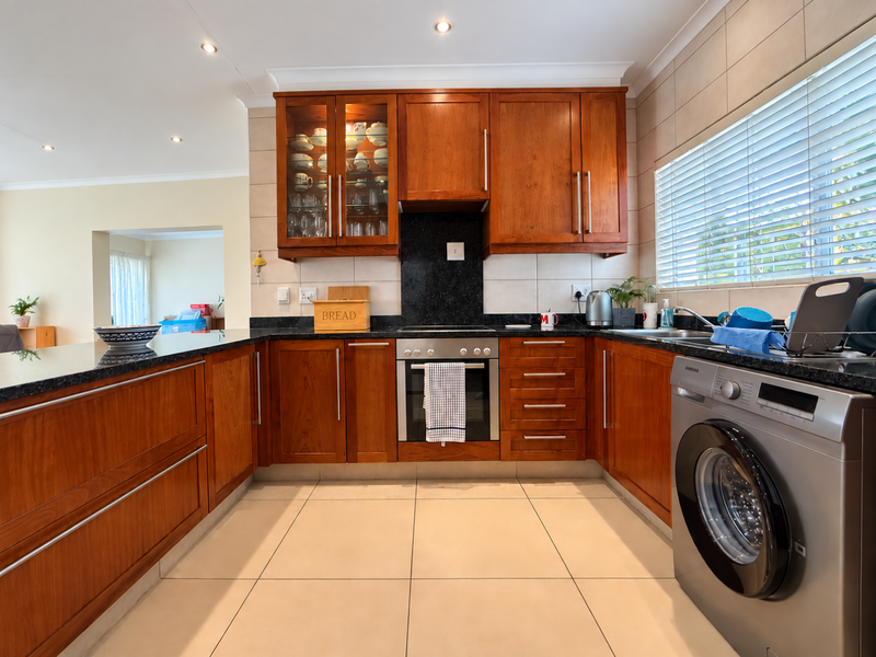 A well-maintained kitchen featuring warm wooden cabinetry, granite countertops, built-in oven, and tiled finishes, offering a functional and classic cooking space.