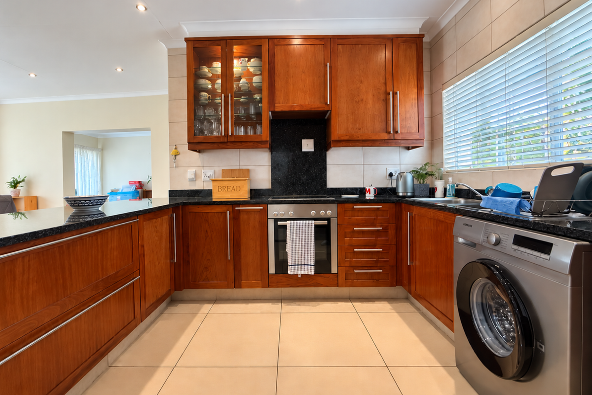 A well-maintained kitchen featuring warm wooden cabinetry, granite countertops, built-in oven, and tiled finishes, offering a functional and classic cooking space.