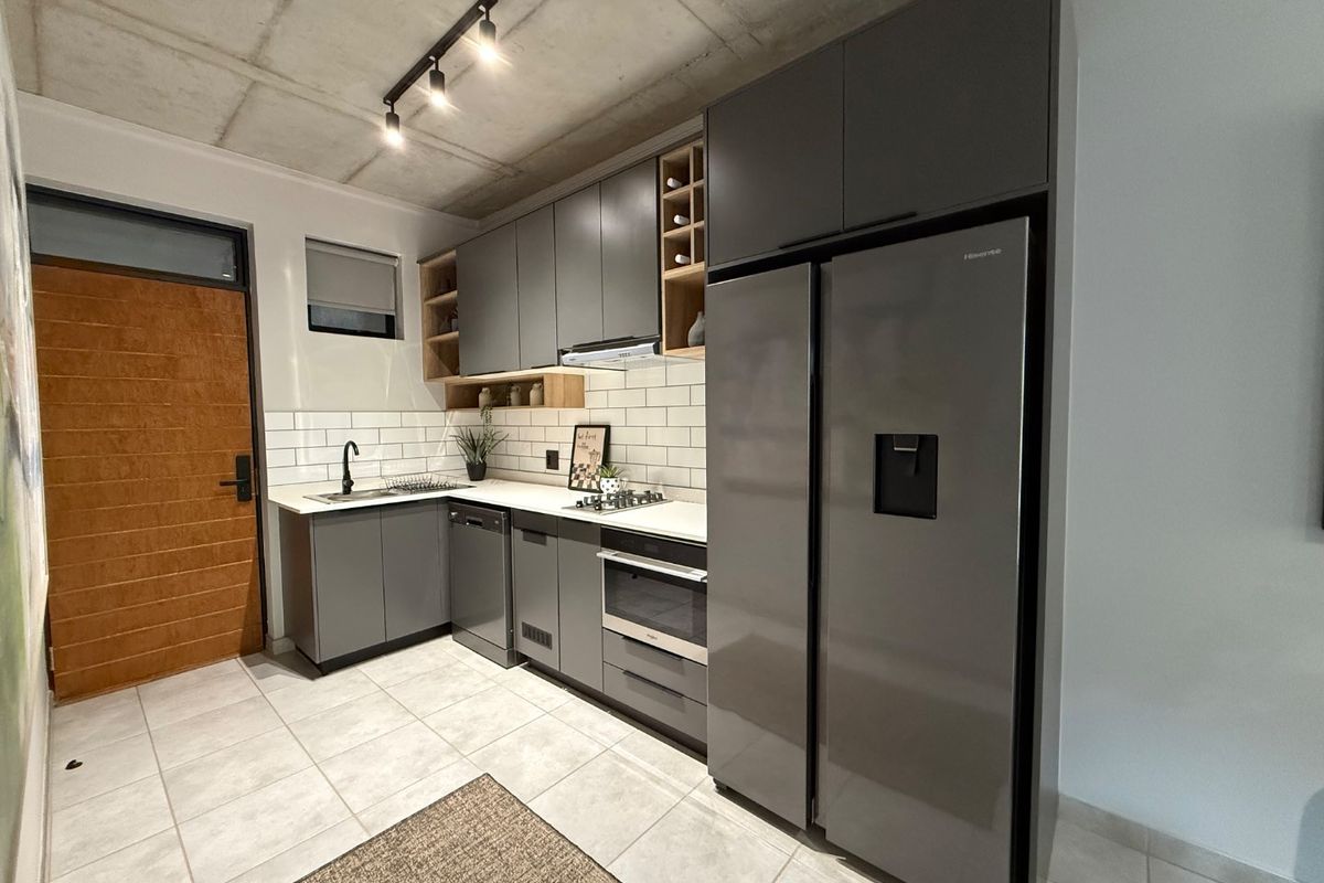 Modern kitchen featuring sleek grey cabinetry, subway tile backsplash, built-in appliances, and an industrial-style exposed concrete ceiling with track lighting.