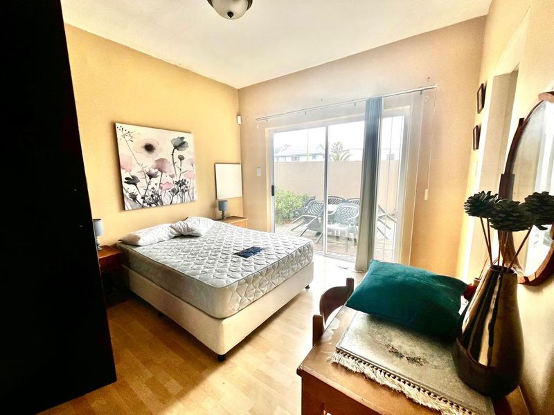 Bedroom featuring laminate flooring, a built-in cupboard, and a sliding glass door providing access to an outdoor patio area.