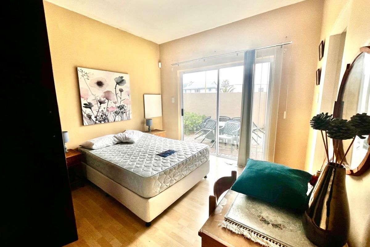 Bedroom featuring laminate flooring, a built-in cupboard, and a sliding glass door providing access to an outdoor patio area.