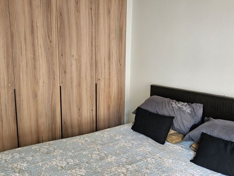 A bedroom featuring modern wood-grain built-in wardrobes providing ample storage space.