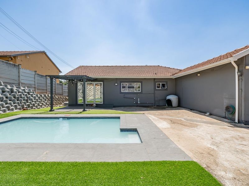 Rear exterior view featuring a swimming pool, pergola, and a large unfinished concrete patio area adjacent to the main house structure.