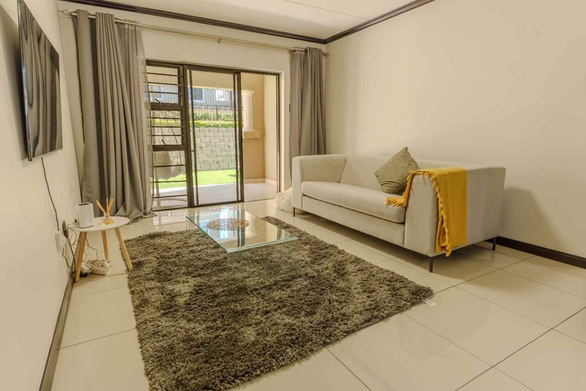 A bright living room featuring tiled flooring and a sliding glass door that provides direct access to an outdoor patio area.