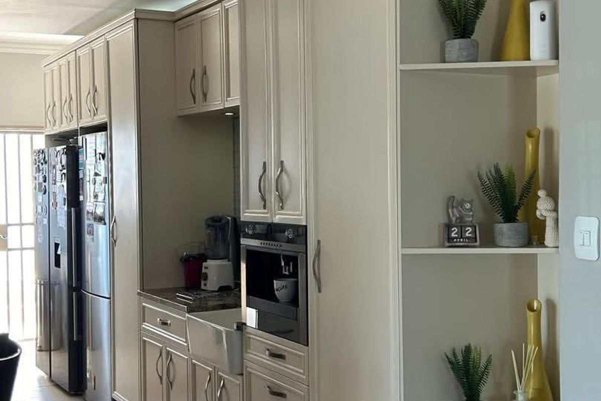 A well-maintained kitchen featuring cream-colored cabinetry, a farmhouse-style sink, and integrated oven, providing a clean and functional culinary space.