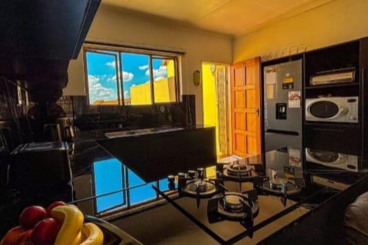 A modern kitchen featuring sleek black countertops, a built-in gas hob, and integrated cabinetry with direct access to an exterior door.