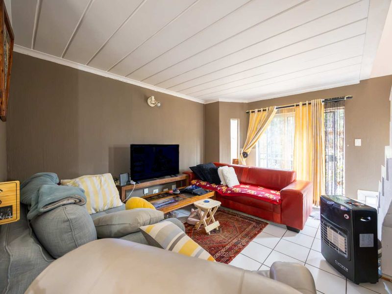 A living room featuring tiled flooring, a tongue and groove ceiling, and a sliding glass door providing access to the exterior.