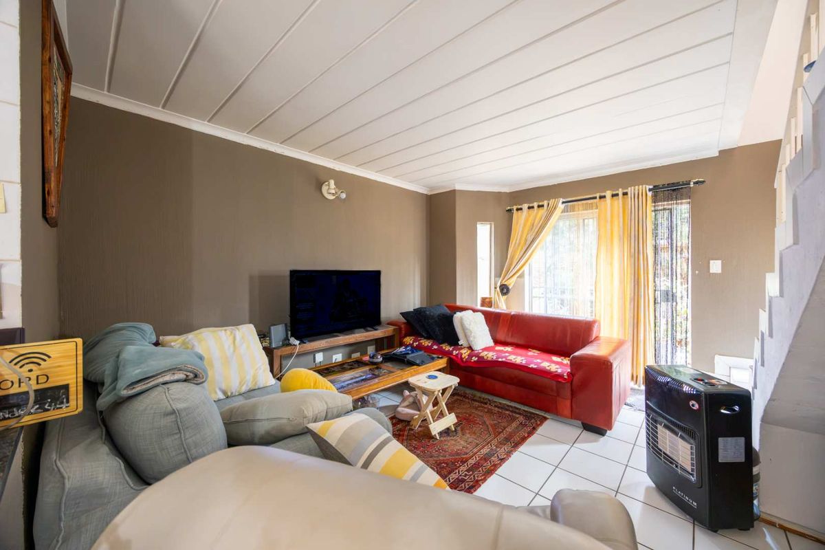 A living room featuring tiled flooring, a tongue and groove ceiling, and a sliding glass door providing access to the exterior.