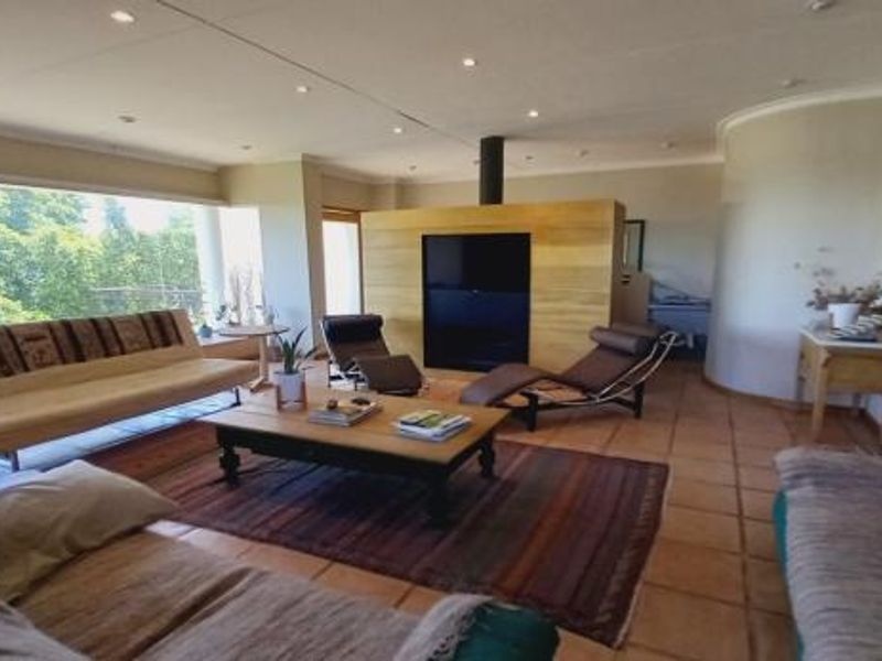 Spacious living room featuring large picture windows, tiled flooring, recessed lighting, and a central fireplace, offering a bright and open atmosphere.
