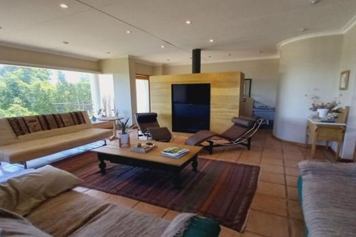 Spacious living room featuring large picture windows, tiled flooring, recessed lighting, and a central fireplace, offering a bright and open atmosphere.