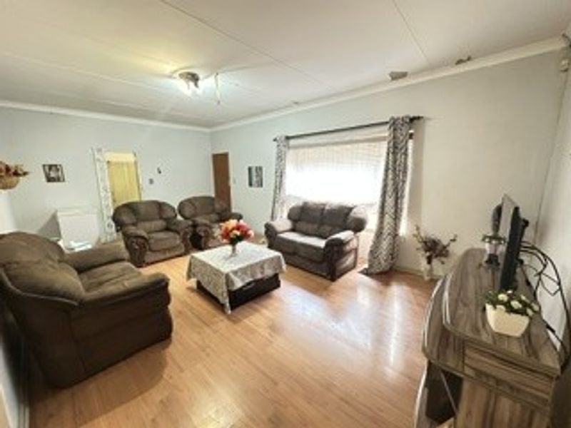A spacious living room featuring laminate flooring and coved ceilings, offering a comfortable area for relaxation and family gatherings.