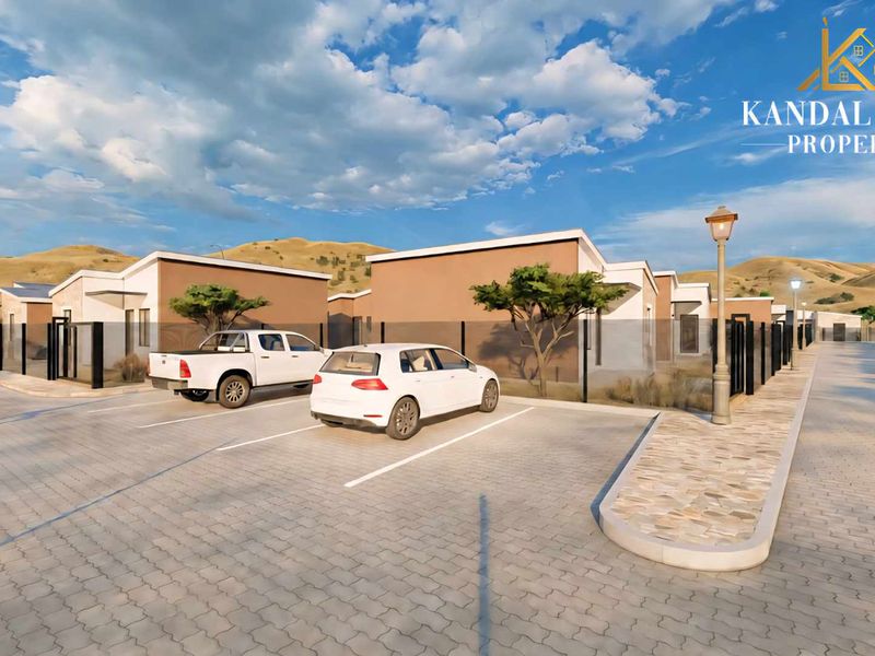A digital rendering of a modern townhouse development featuring paved parking areas, perimeter fencing, and landscaped grounds under a clear sky.