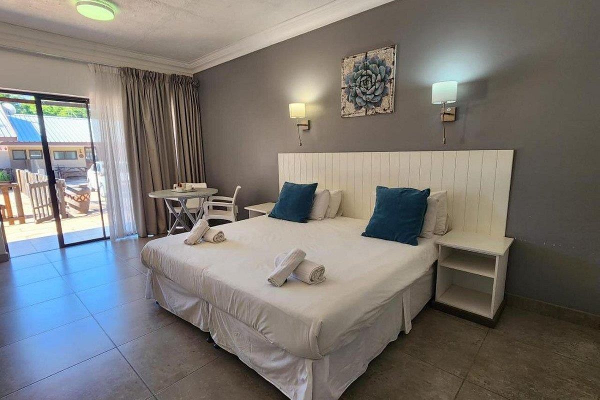 A comfortable bedroom featuring tiled flooring, a built-in headboard, wall-mounted lighting, and sliding glass doors providing direct access to an outdoor patio area.