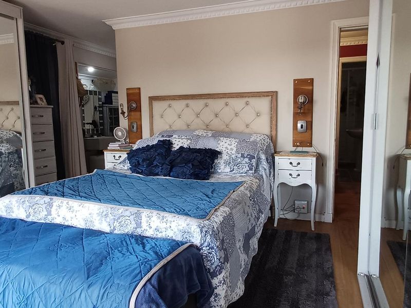 A bedroom featuring laminate flooring, crown molding, and a large built-in mirrored wardrobe providing ample storage space.