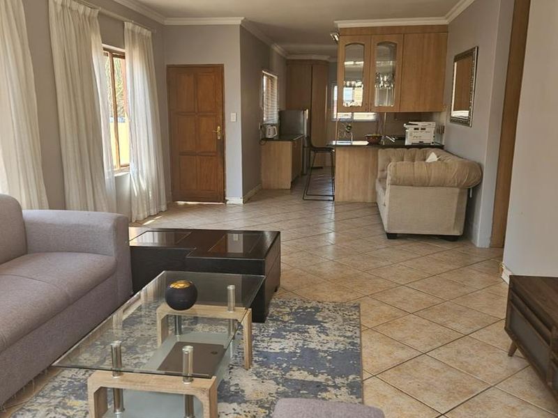 Open plan living area featuring tiled flooring, recessed lighting, and a functional kitchen with wooden cabinetry and a breakfast counter.