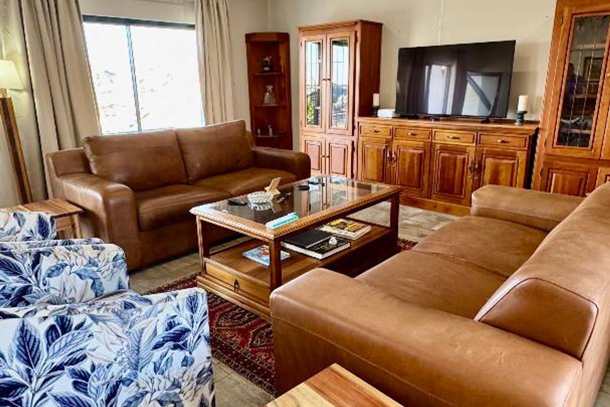 A comfortable living room featuring tiled flooring, recessed ceiling lighting, and large windows allowing for natural light.