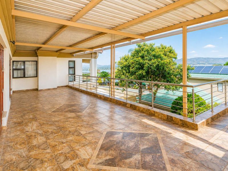 Spacious covered balcony featuring tiled flooring, stainless steel balustrades, and expansive views of the surrounding area.