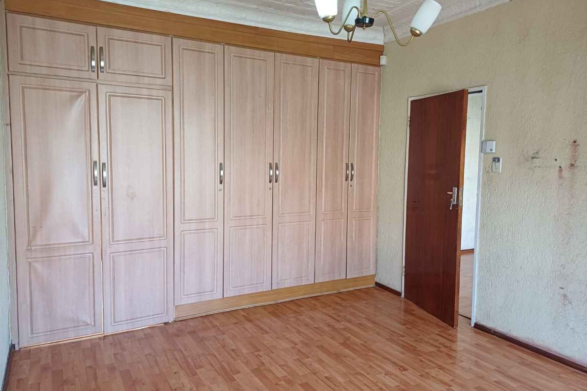 A bedroom featuring extensive built-in wooden cabinetry, laminate flooring, and a textured ceiling finish.