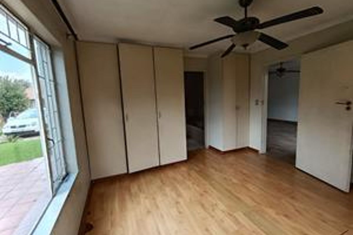 A bedroom featuring built-in cupboards, laminate flooring, and a ceiling fan, with direct access to an outdoor patio area.
