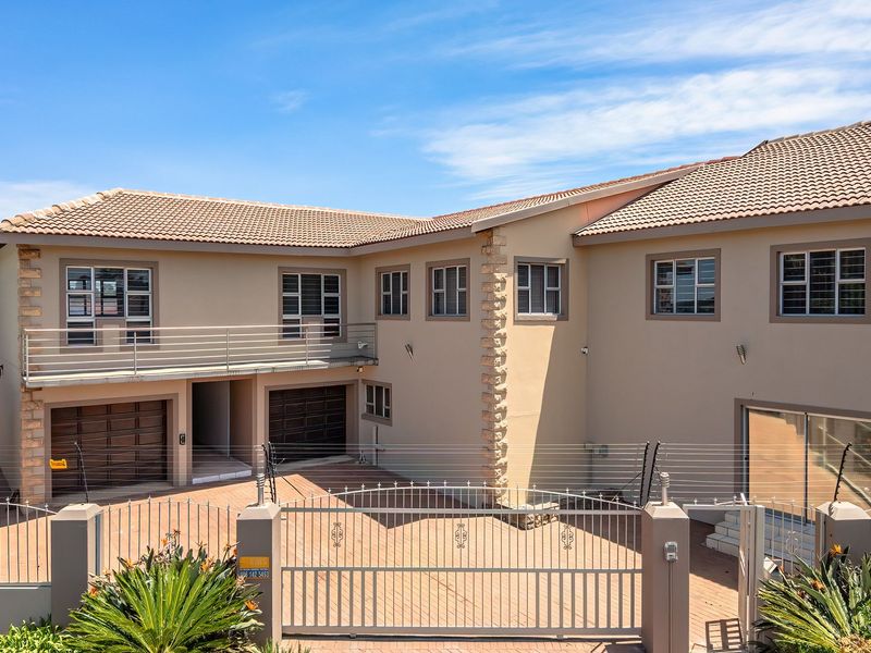 A well-maintained double-story residential property featuring a paved driveway, double garage, upper-level balcony, and secure perimeter fencing.