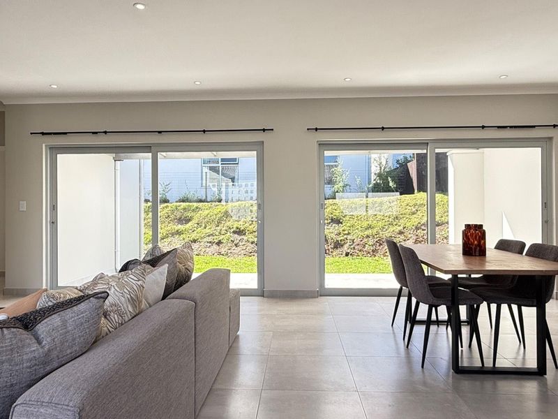 Spacious open-plan living and dining area featuring large sliding glass doors that provide abundant natural light and direct access to the garden.