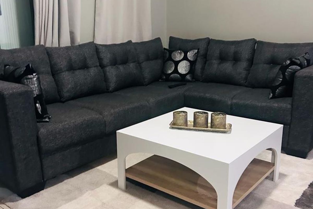 A comfortable living room area featuring neutral tiled flooring and curtain tracks, providing a clean and functional space for relaxation.