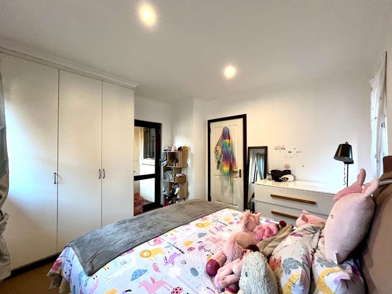 A functional bedroom featuring built-in cupboards, recessed downlighting, and neutral finishes, providing a comfortable and practical living space.