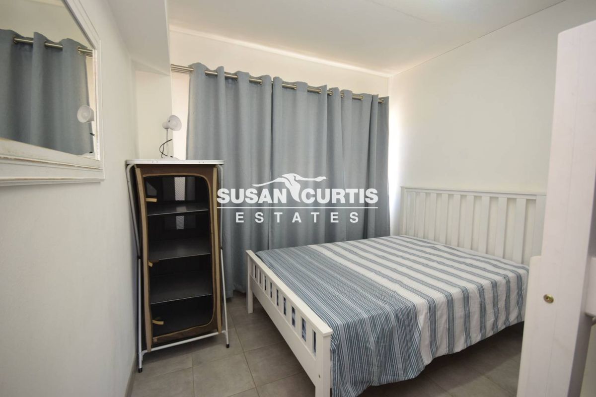 A functional bedroom featuring tiled flooring and neutral wall finishes, providing a clean and simple living space.