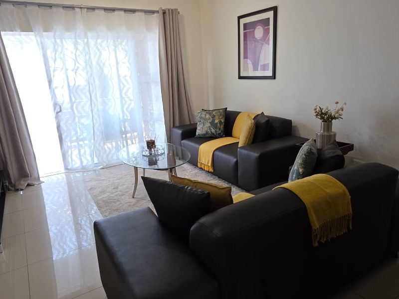 A well-maintained living room featuring polished tiled flooring and a large sliding glass door that provides ample natural light.