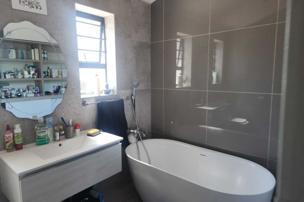 Modern bathroom featuring a freestanding bathtub, wall-mounted vanity with integrated basin, and large format wall tiling.