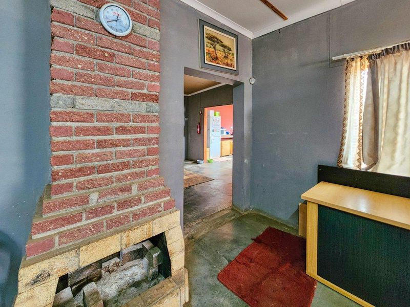 Living room featuring a prominent brick fireplace and concrete flooring, with an open doorway leading through to the kitchen area.