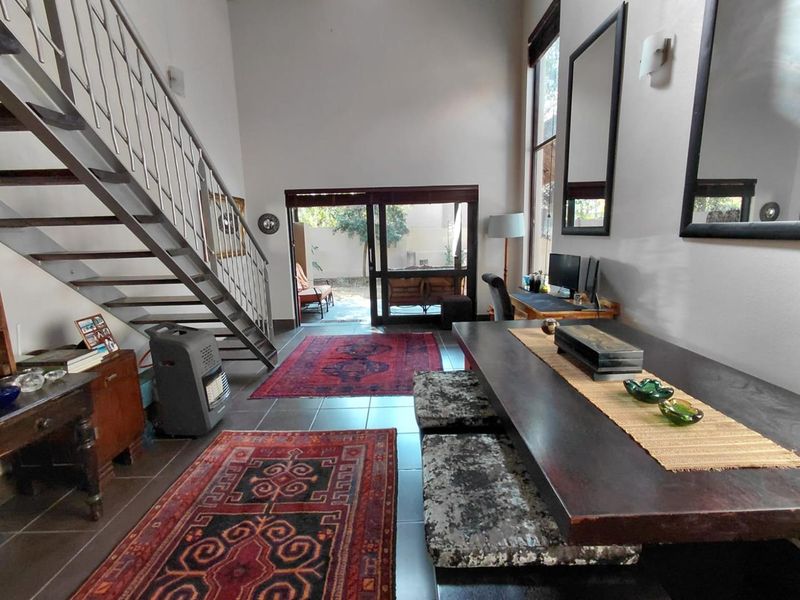 Spacious open-plan living area featuring high ceilings, a modern metal staircase, and large sliding glass doors providing seamless access to the outdoor patio.